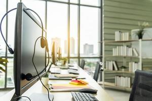 linha de computadores com fones de ouvido na mesa do call center, suporte de comunicação, fone de ouvido voip no teclado do computador portátil. foto