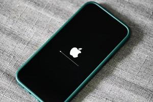 iphone 13 pro com logotipo da apple carregando e instalando o sistema operacional ios 15.5 na tela de perto, novo ios 2022 em dispositivos apple sub v. ios 15 para atualizações bangkok, tailândia - 29 de maio de 2022 foto