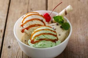 pistache de bola e sorvete branco em uma tigela com caramelo foto