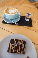 xícara de café cappuccino quente na mesa com bolo de chocolate foto