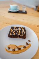 xícara de café cappuccino quente na mesa com bolo de chocolate foto