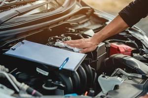 o mecânico do carro está verificando a condição do carro e está usando o pano para limpar o motor. foto