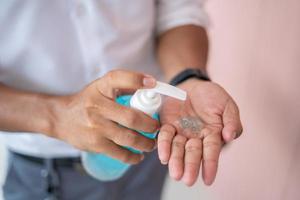as mãos dos homens usam desinfetante para as mãos, gel de lavagem das mãos, bomba dispensadora para prevenir doenças transmissíveis. foto