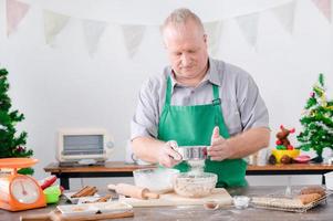 um pai europeu peneirou farinha e preparou ingredientes para assar pão de gengibre, que ele e sua família fizeram para o natal e ano novo foto