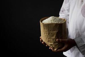 mão muçulmana segurando o saco de esmolas de arroz isolado no fundo preto foto