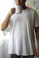 recortado de homem de camiseta simples segurando caneca de porcelana para maquete foto