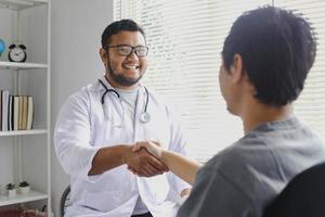 feliz sorridente médico cumprimenta seu paciente apertando as mãos foto