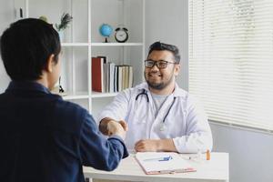 feliz sorridente médico cumprimenta seu paciente apertando as mãos foto