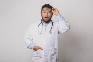 médico masculino com expressão de surpresa ao levantar os óculos isolados no fundo branco foto