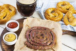 menu de comida para oktoberfest. salsicha com molho diferente, pretzel e copo de cerveja escura foto