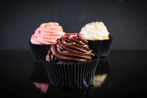 saborosos cupcakes coloridos isolados em fundo escuro. bolinho delicioso foto
