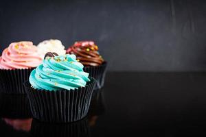 saborosos cupcakes coloridos isolados em fundo escuro. bolinho delicioso foto