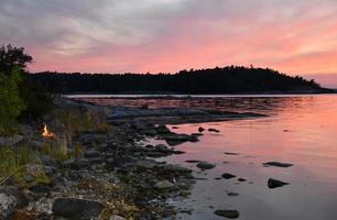 pôr do sol vermelho sobre um acampamento na ilha com lareira foto