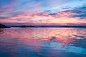 azul rosa magnífico pôr do sol acima de um lago de água espelho na suécia foto