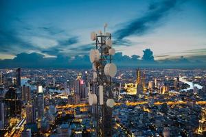 torre de telecomunicações com onda de antena de rede celular 5g no fundo da cidade à noite foto
