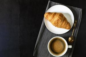 café da manhã café e croissant no prato na mesa de madeira. foto