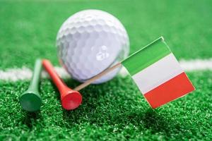 bola de golfe com bandeira da itália e tee no gramado verde ou grama é o esporte mais popular do mundo. foto