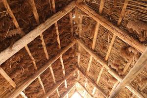 o telhado de junco da casa. materiais de construção naturais. textura do velho telhado de palha por dentro. tecnologia antiga. arquitetura de casa de madeira. foto