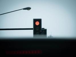 vista de dentro de um carro de um semáforo vermelho sobre interseção urbana. conceito de transporte e regulação.