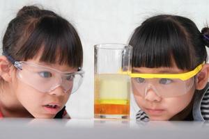 as crianças estão aprendendo e fazendo experimentos científicos na sala de aula. duas irmãzinhas brincando de experimento científico para estudar em casa. experimentos científicos fáceis e divertidos para crianças em casa. foto