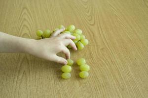 uvas e uma mão de criança. conceito de comida saudável. fotografia de alimentos. foto