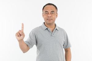 retrato de homem asiático sênior de meia-idade em um pano cinza claro, levantando e mostrando um dedo. isolar no fundo branco. foto