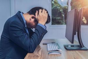 empresário sentado estressado na frente de um computador foto