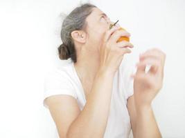 mulher de quarenta e nove anos em uma camiseta branca contra um fundo branco com uma laranja foto