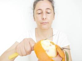 mulher de quarenta e nove anos em uma camiseta branca contra um fundo branco com uma laranja foto