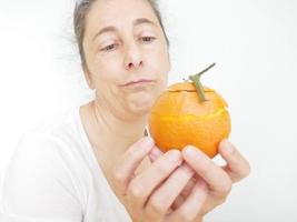 mulher de quarenta e nove anos em uma camiseta branca contra um fundo branco com uma laranja foto