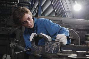 uma jovem profissional engenheira da indústria trabalha em um uniforme de segurança com ferramentas de precisão de metalurgia, tornos mecânicos e oficina de peças de reposição na fábrica de fabricação de aço. foto