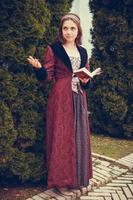 retrato de mulher morena vestida com roupas barrocas históricas lendo livro, ao ar livre foto
