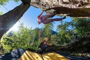 prática de boulder. subindo alguns metros do chão. duas garotas com o crash pad foto