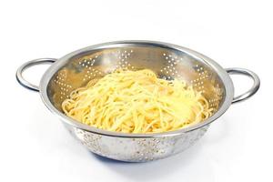 espaguete cozido fresco no filtro de aço inoxidável isolado no branco foto