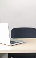 local de trabalho vazio com laptop em uma mesa de madeira. cadeira de escritório preta. copie o espaço. tamanho vertical. foto