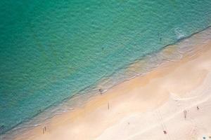 vista aérea praia arenosa e ondas pessoas relaxando na praia lindo mar tropical de manhã imagem de temporada de verão por vista aérea tiro com drone, vista de alto ângulo de cima para baixo ondas do mar foto