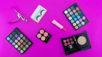 paleta de sombras bonitas multicoloridas e vários acessórios cosméticos para maquiagem em fundo rosa produtos de beleza maquiagem sombra de olho cosmética de verão foto