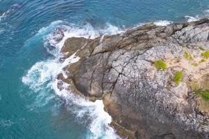 vista aérea de cima para baixo onda grande à beira-mar batendo no penhasco de rocha bela superfície do mar escuro em dia ensolarado fundo de verão incrível vista do mar vista superior litoral em phuket tailândia foto