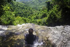 mulher sentada em waterfall.young relaxando em cachoeira.bom conceito saudável,peaceful.photo viagens e estilo de vida. foto
