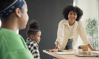 sala de aula com diversos alunos de estudantes afro-americanos felizes e professores fazendo atividades juntos. o professor está ensinando, orientando e conversando com as crianças de diversas maneiras. foto