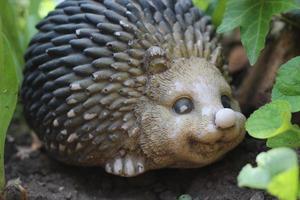 retrato de um ouriço animal no jardim em flores, escultura de decoração para o jardim foto