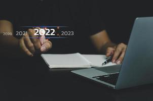 mão de empresário tocando o número de 2022 anos no conceito de tela virtual tendências digitais indústria e tendência de negócios. copie o espaço. foto