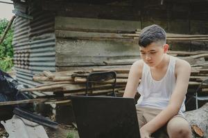 menino asiático estudando online com computador portátil em sua mesa em casa rural, aprendendo com professor em casa, ensino à distância aprender online internet rural, falta de equipamentos educacionais foto