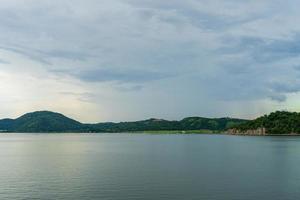 bela vista da barragem do reservatório cercada por montanhas na província de kanchanaburi, tailândia. foto