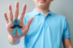 novembro mês de conscientização do câncer de próstata, homem segurando fita azul com bigode para apoiar pessoas que vivem e doenças. cuidados de saúde, homens internacionais, pai e conceito de dia mundial do câncer foto