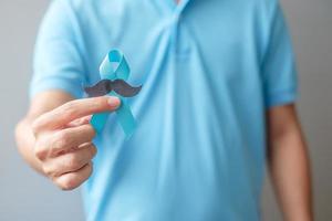 novembro mês de conscientização do câncer de próstata, homem segurando fita azul com bigode para apoiar pessoas que vivem e doenças. cuidados de saúde, homens internacionais, pai e conceito de dia mundial do câncer foto