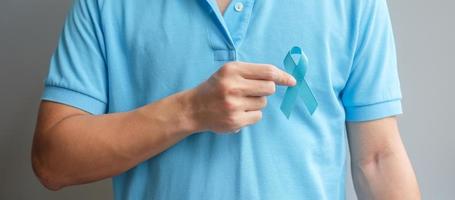 mês de conscientização do câncer de próstata de novembro, homem de camisa azul com a mão segurando a fita azul para apoiar as pessoas que vivem e estão doentes. cuidados de saúde, homens internacionais, pai e conceito de dia mundial do câncer foto