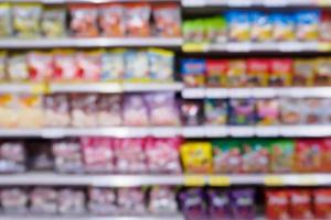 supermercado borrão abstrato com variedade de salgadinhos chips de produtos alimentícios nas prateleiras da loja foto