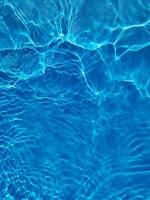 desfocar a textura de superfície de água calma de cor azul transparente turva com salpicos e bolhas. fundo de natureza abstrata na moda. ondas de água na luz solar. foto