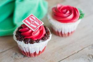 cupcakes de rosas vermelhas na mesa de madeira foto